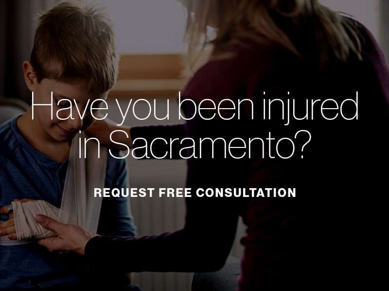 A mother comforting her son with a broken arm with the text "Have you been injured in Sacramento? Request free consultation" superimposed
