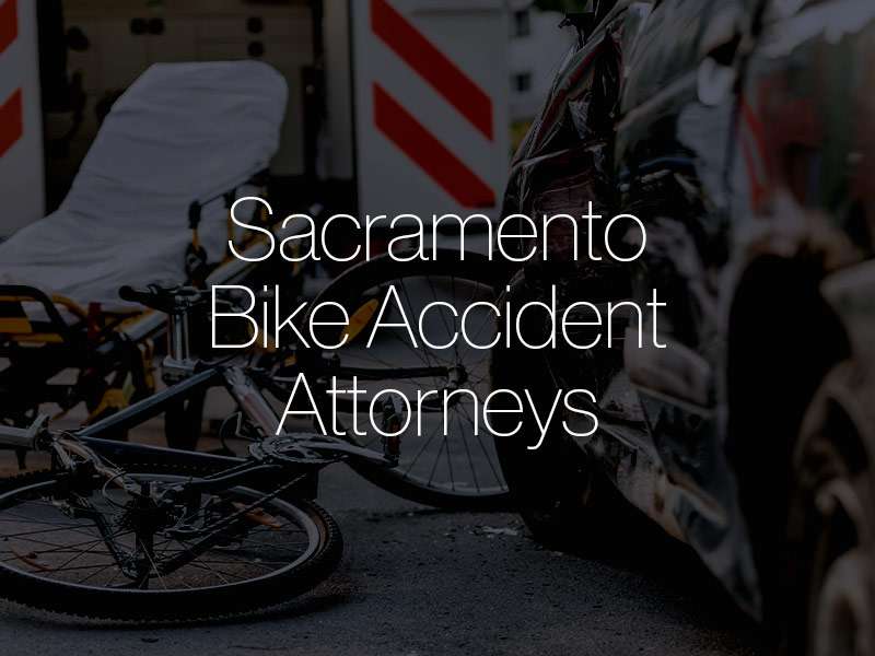 A crashed bicycle outside of an ambulance with the text "Sacramento Bike Accident Attorneys" superimposed